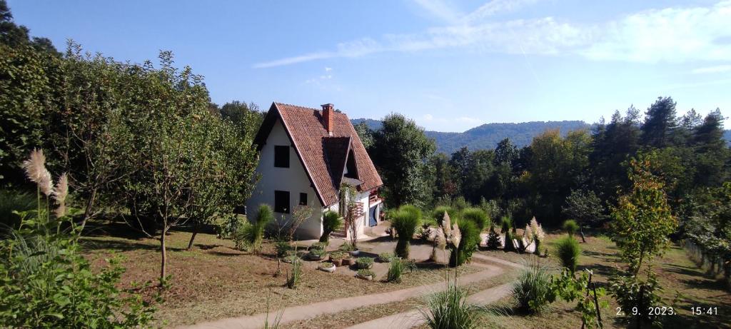 une petite maison blanche dans un champ arboré dans l'établissement Vikendica Popović, à Doboj