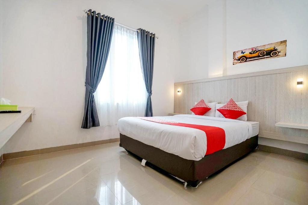 a bedroom with a large bed with red pillows at OYO Life 1299 Balcony Orange Homestay in Palembang