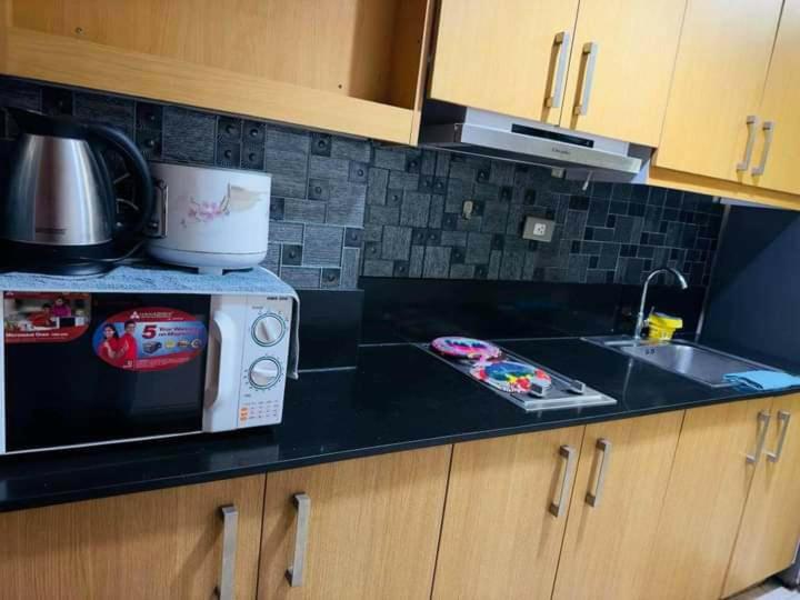 a kitchen counter with a microwave and a sink at SHELL RESIDENCE in Manila