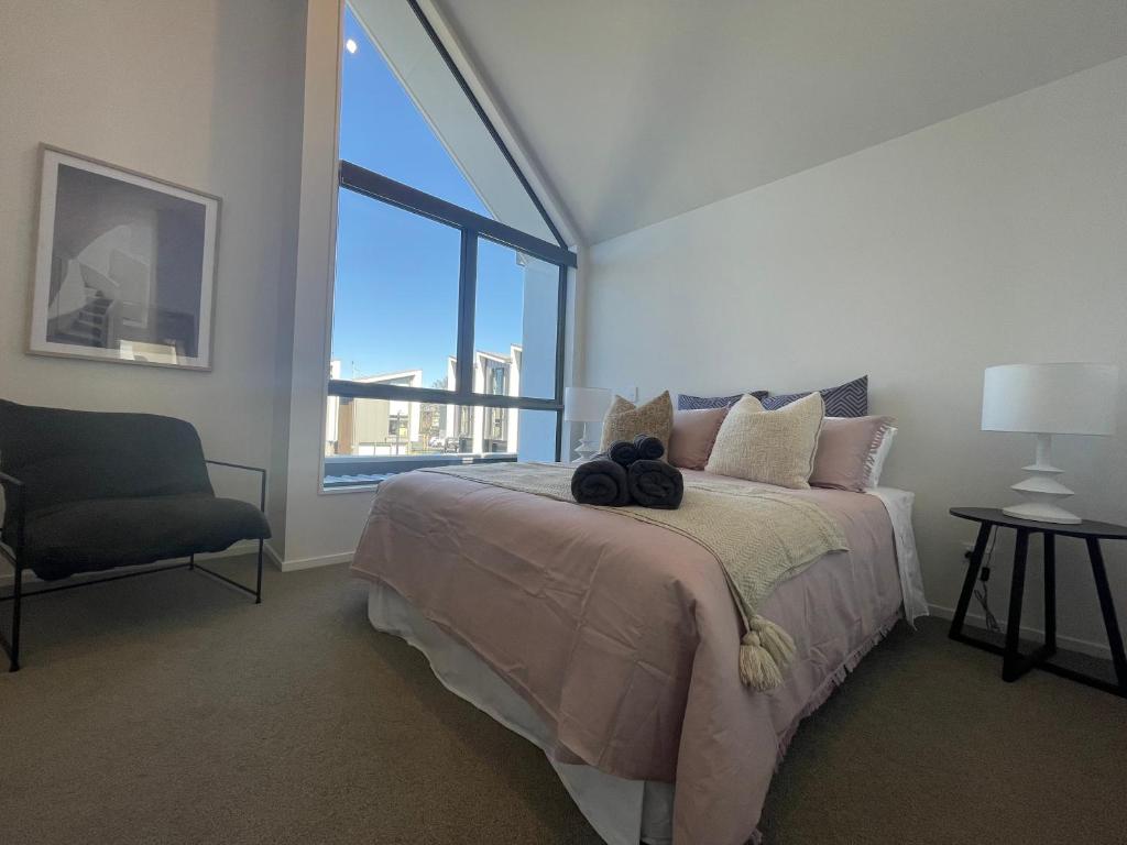 a bedroom with a bed and a chair and a window at Inner City Luxury With Free Parking in Christchurch