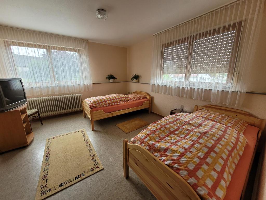 a bedroom with two beds and a tv and windows at Gasthaus Ratsschenke in Niederzissen