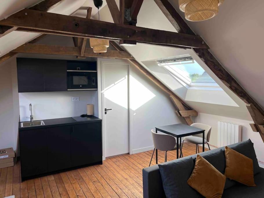 a kitchen and a living room with a couch and a table at Studio moderne en centre ville in Guipel