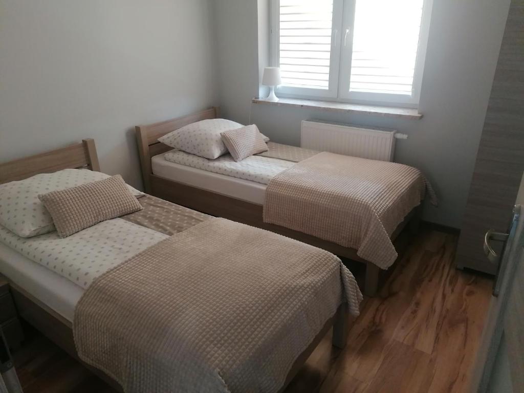 two beds in a small room with a window at Apartament z tarasem in Bodzentyn