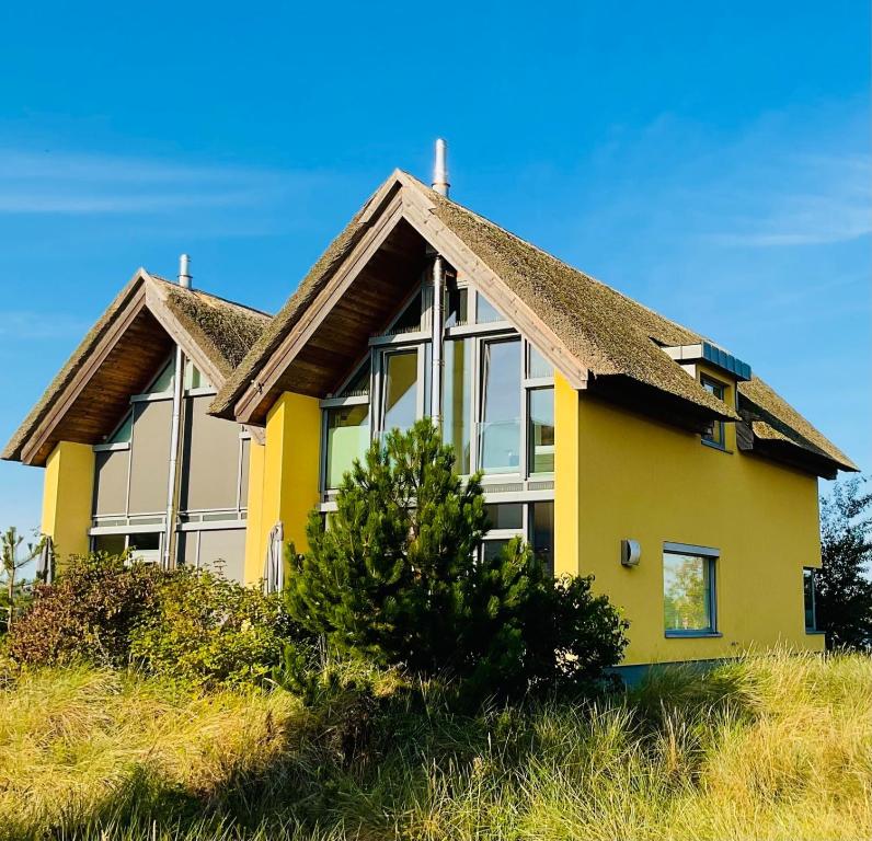 ハイリゲンハーフェンにあるOstsee - Reetdachhaus Nr 8 "Sonne und mehr" im Strand Resortの草の丘の上の黄色い家