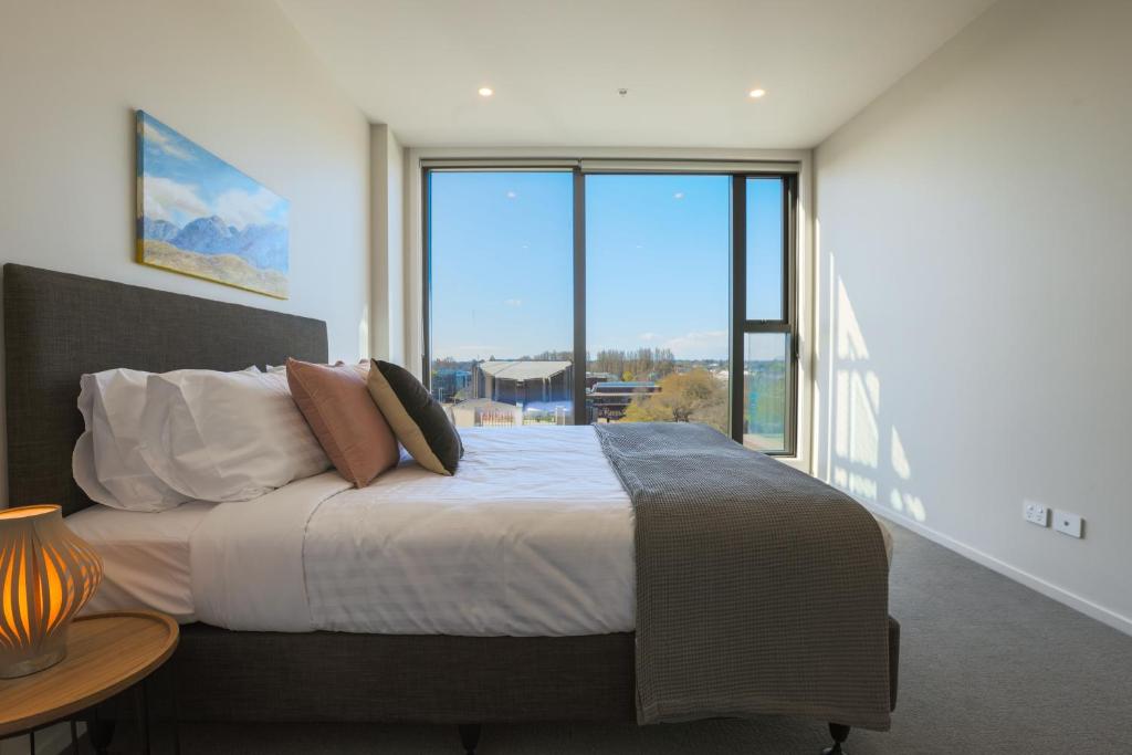 a bedroom with a large bed with a large window at Luxury 2 Bedroom CBD Apartment with Free Parking in Christchurch