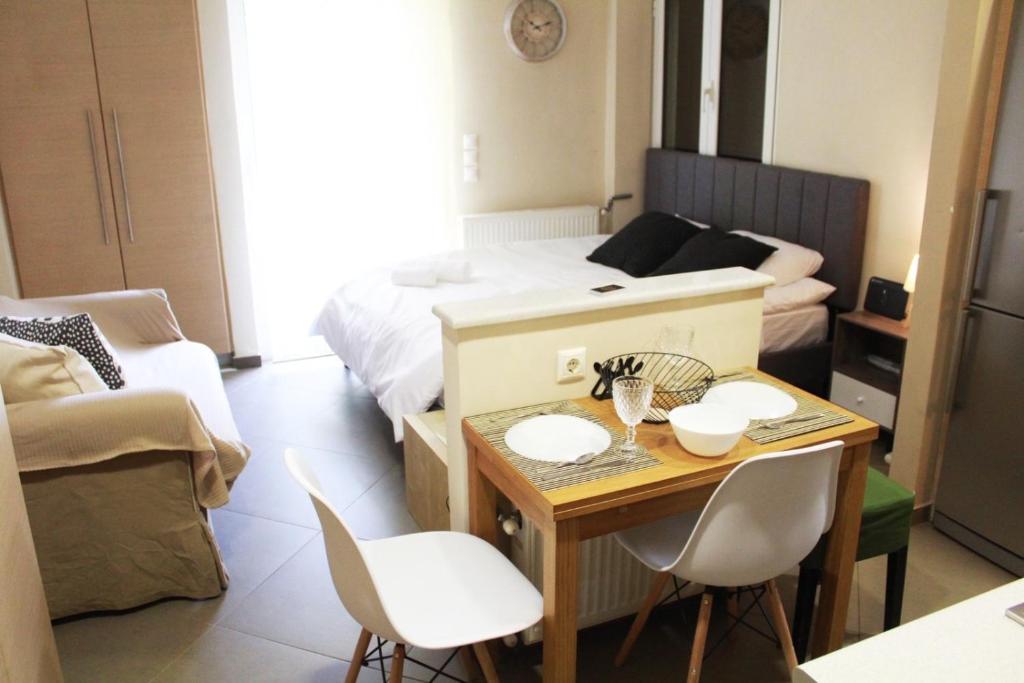 Habitación pequeña con cama, mesa y sillas en AIOLOS VOULA near the sea apartment, en Atenas