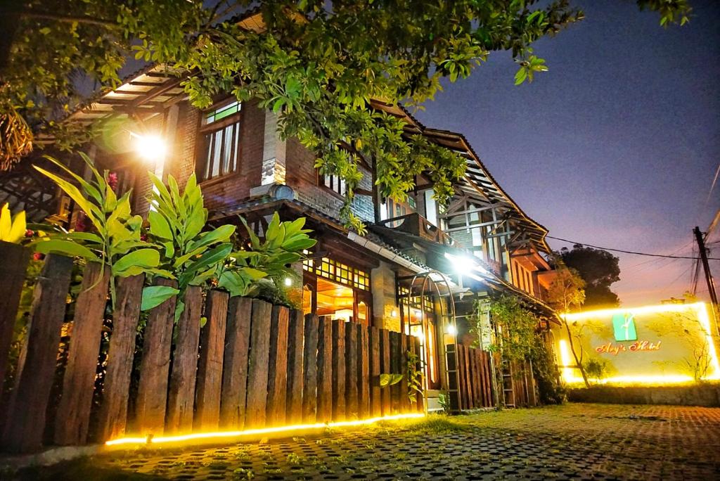 a wooden house with lights in front of a fence at Ary's Hotel by Cocotel in Yogyakarta