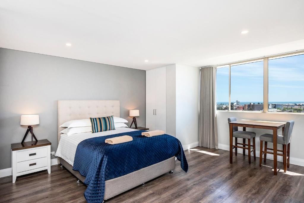 um quarto com uma cama, uma secretária e uma janela em The Allegra - 180 degree ocean and city views em Fremantle