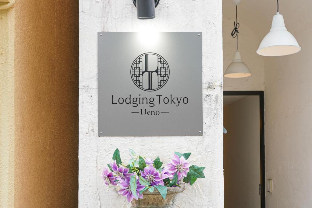 東京的住宿－Lodging Tokyo Ueno，花瓶里紫色花的墙上的标志