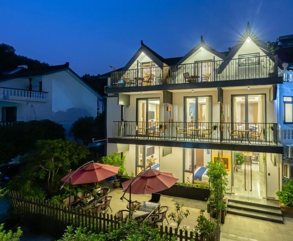 a building with tables and umbrellas in front of it at Hangzhou Ziwei Boutique Homestay in Hangzhou