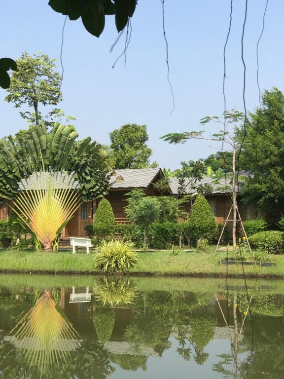 a house with a pond in front of it at Sripiamsuk Resort Bangkok in Pathum Thani