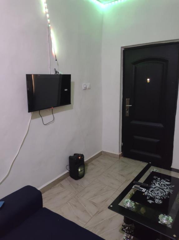 uma sala de estar com televisão e uma porta preta em Kingee Lodge em Sunyani