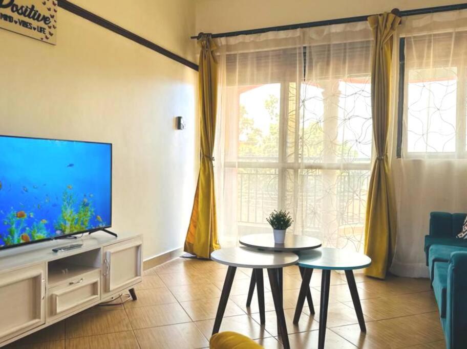 uma sala de estar com uma televisão de ecrã plano e uma mesa em Chayil Loft Mulago em Kampala