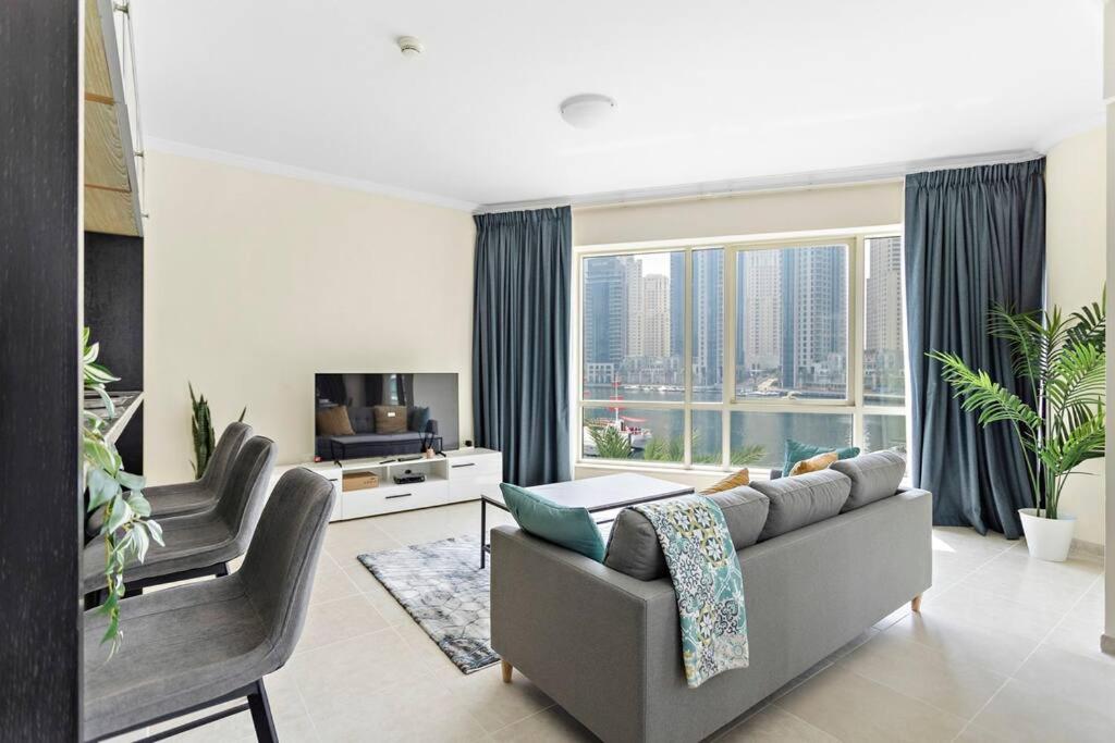 a living room with a couch and a large window at StoneTree - Stylish 2BR with Dubai Marina Canal View in Dubai