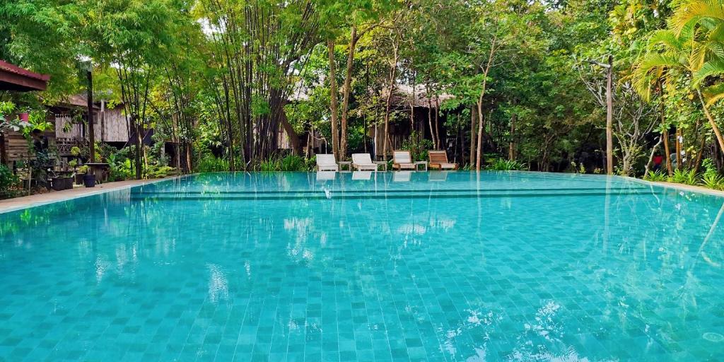 a large swimming pool with chairs and trees at Palm Village Resort & Spa in Siem Reap