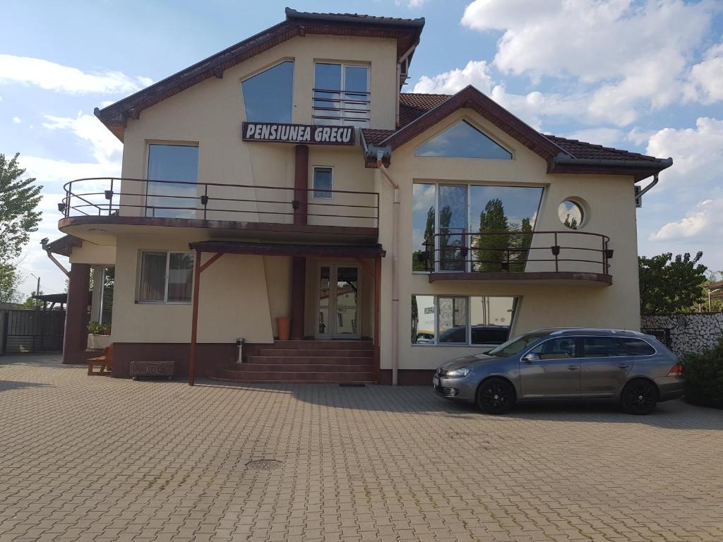 un bâtiment avec une voiture garée devant lui dans l'établissement pensiunea grecu, à Lugoj