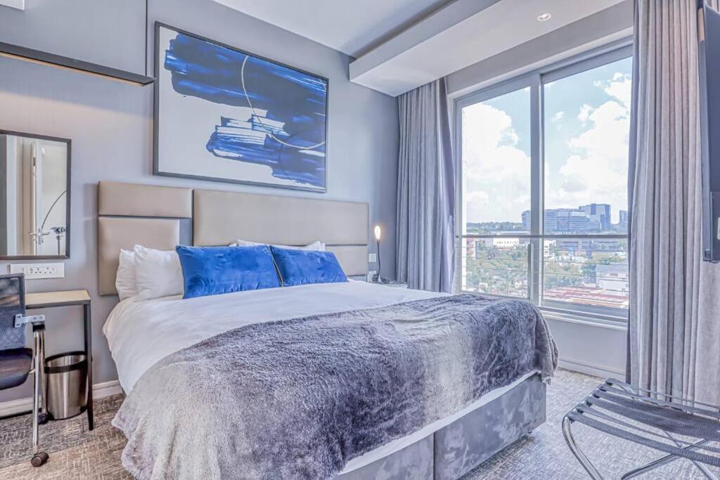 a bedroom with a large bed and a large window at 1 bed Luxury Apartment with pool in Johannesburg