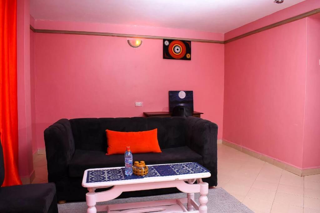 ein Wohnzimmer mit einem schwarzen Sofa und einem Tisch in der Unterkunft EP Home in Meru