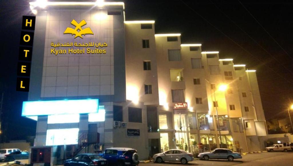 um edifício com carros estacionados em frente a ele à noite em Kyan Abha Hotel - فندق كيان ابها em Abha