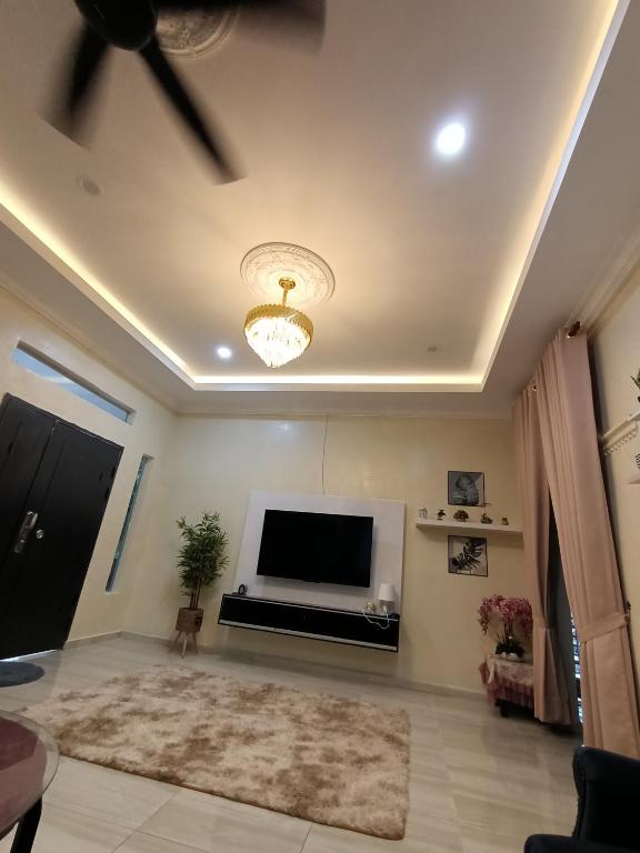 a living room with a television and a ceiling fan at Cp homestay in Batu Kurau