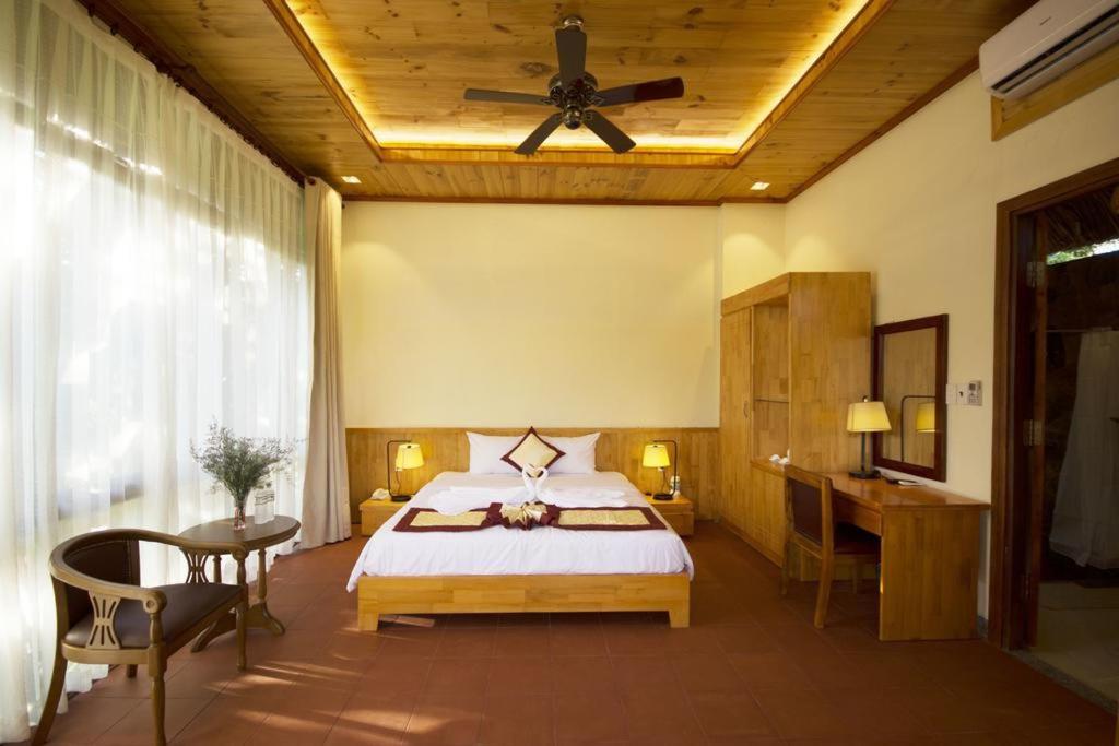 a bedroom with a bed and a ceiling fan at Paradiso Phu Quoc Resort in Phu Quoc