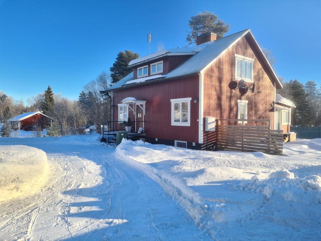 una casa roja con nieve en el suelo en Mattmar vila, 