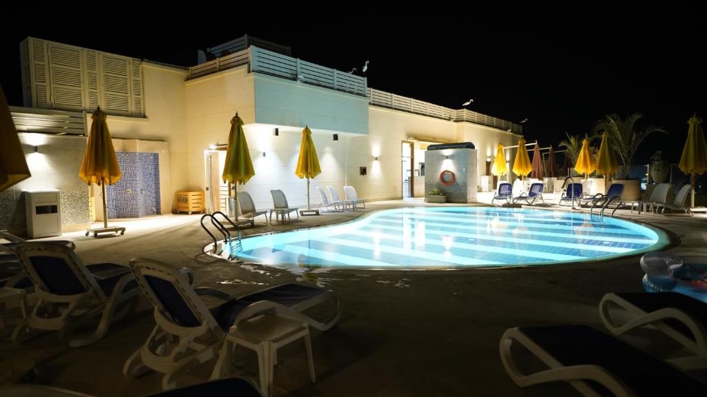 a swimming pool at night with chairs and umbrellas at Holy Family Hotel in Jabal aţ Ţayr