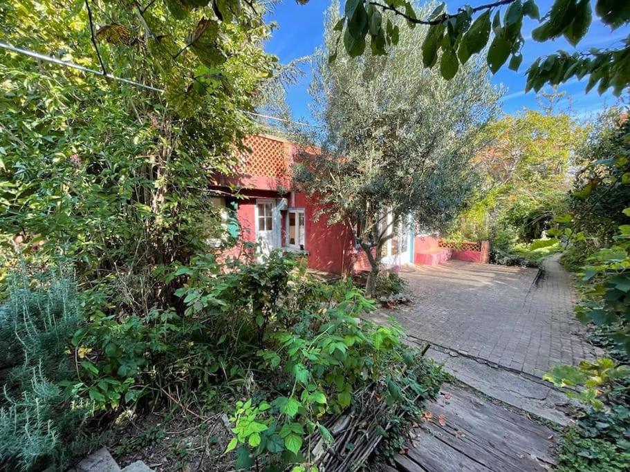 a red house with trees in front of a street at Charmante maison dans jardin, calme, 55m2- 2ch, métro, très proche Paris in Vitry-sur-Seine