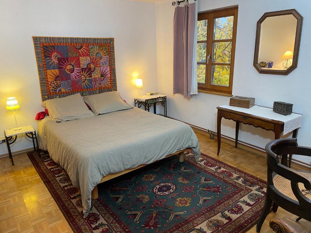 una camera con letto, tavolo e specchio di Chez Rosa a Haguenau
