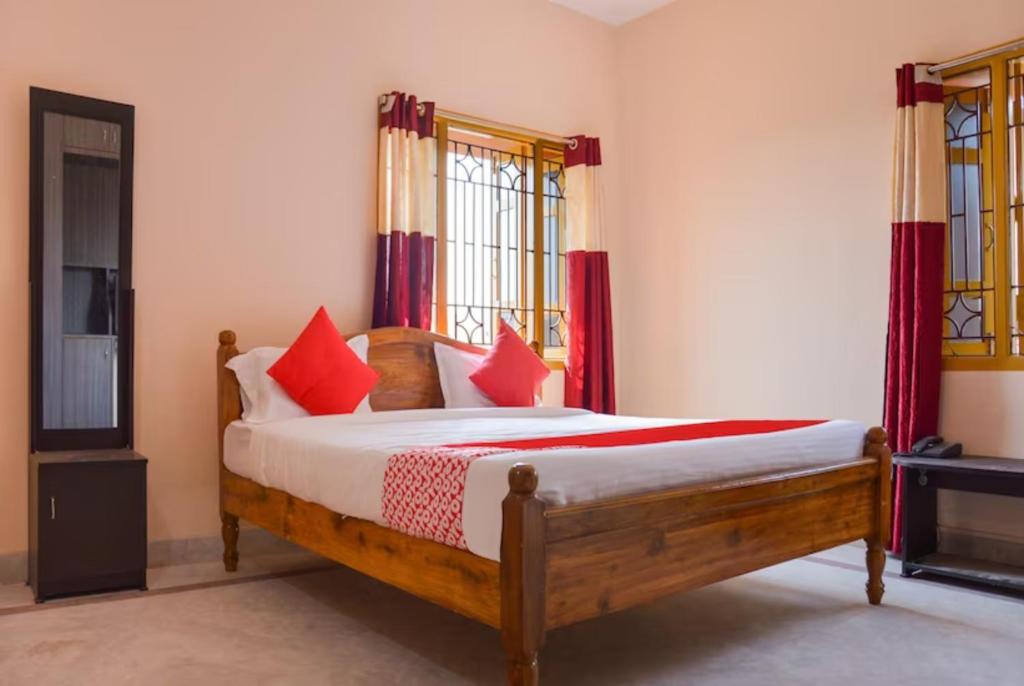 een slaapkamer met een houten bed met rode kussens bij Goroomgo Caroline Homestay Bhubaneswar in Bhubaneshwar