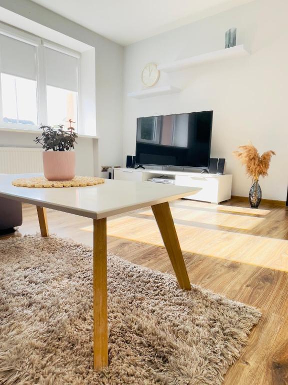 ein Wohnzimmer mit einem Tisch und einem TV in der Unterkunft Celtnieku street apartment in Liepāja