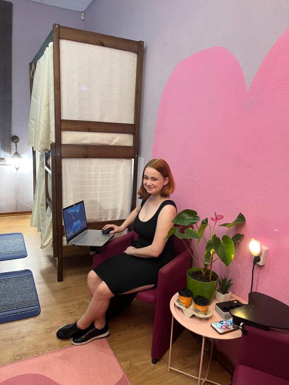 uma mulher sentada numa cadeira com um laptop em ArArAt-PODOL Hostel KYIV em Kiev