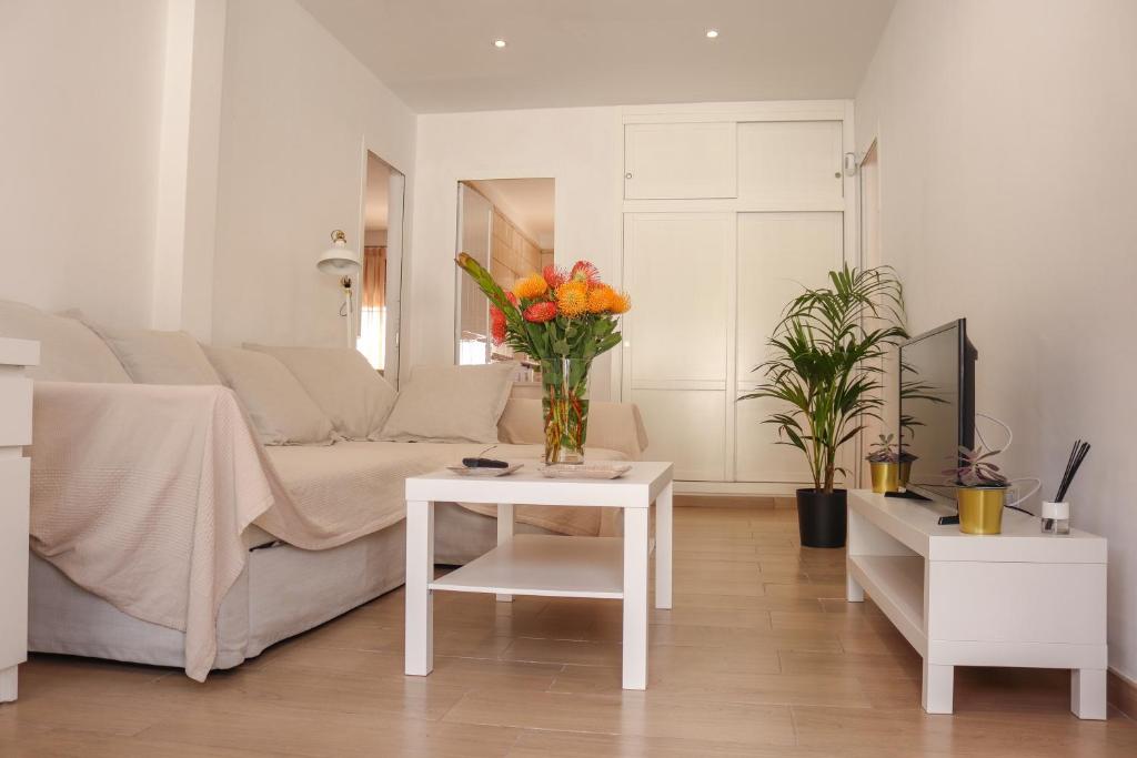 ein Wohnzimmer mit einem Sofa und einem Tisch mit Blumen in der Unterkunft Inés (B): Relax y playa. in Breña Baja