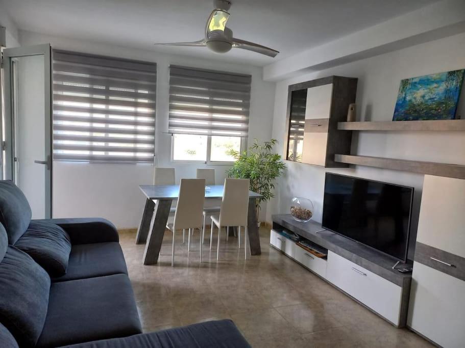 a living room with a dining room table and a tv at Apartamento Playa de Xilxes. in Moncófar