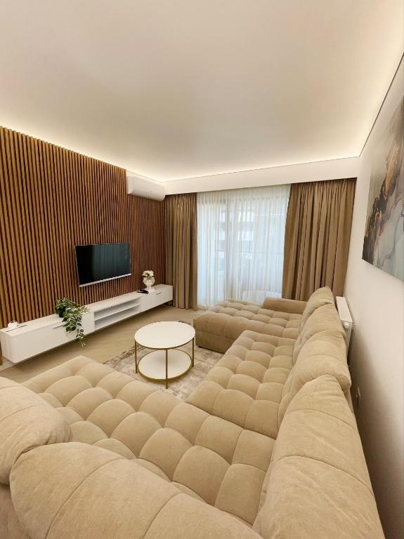 a living room with a large couch in front of a television at Luxury Wellness&Spa- Cortina North in Bucharest