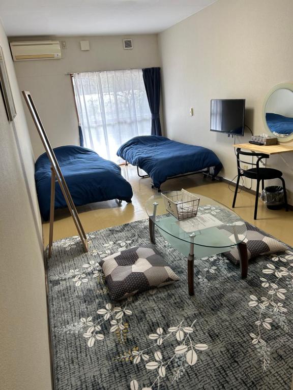 Guest House Koriyama في كورياما: غرفة معيشة بسريرين وطاولة زجاجية