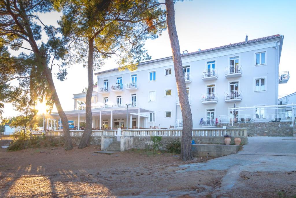 a large white building with trees in front of it at Hotel Bor in Krk