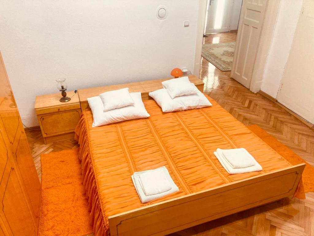 uma grande cama de madeira com almofadas brancas em Eldorado em Sombor