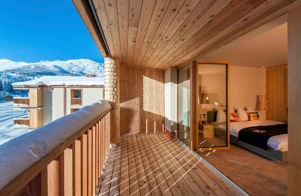 a balcony with a bedroom and a bed and mountains at Bestzeit Lifestyle & Sport Hotel in Parpan