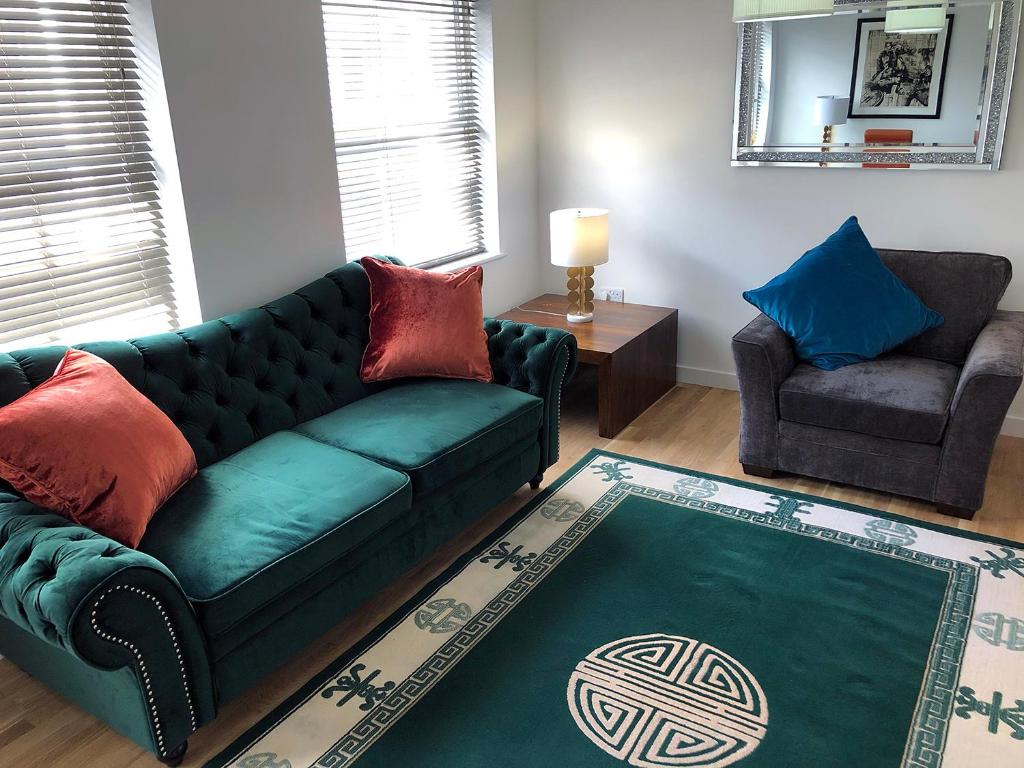 a living room with a green couch and a chair at Crown House is a brand new development with unique features in Newbury