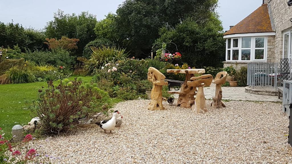 um jardim com um parque infantil com galinhas à volta em Swallows Rest em Weymouth