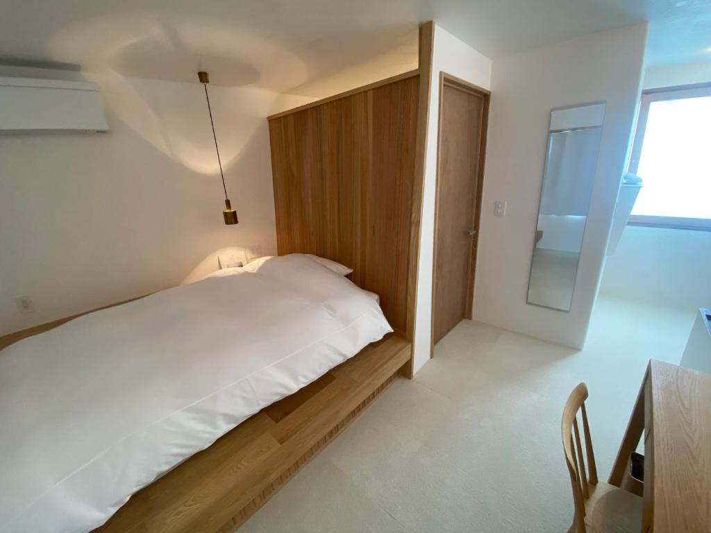 a bedroom with a large white bed and a desk at HUB INN 離れ in Habu