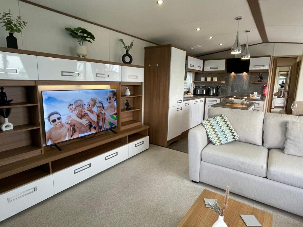 a living room with a couch and a tv at Golden Anchor - The Milano - Coastal Caravan Breaks in Chapel Saint Leonards