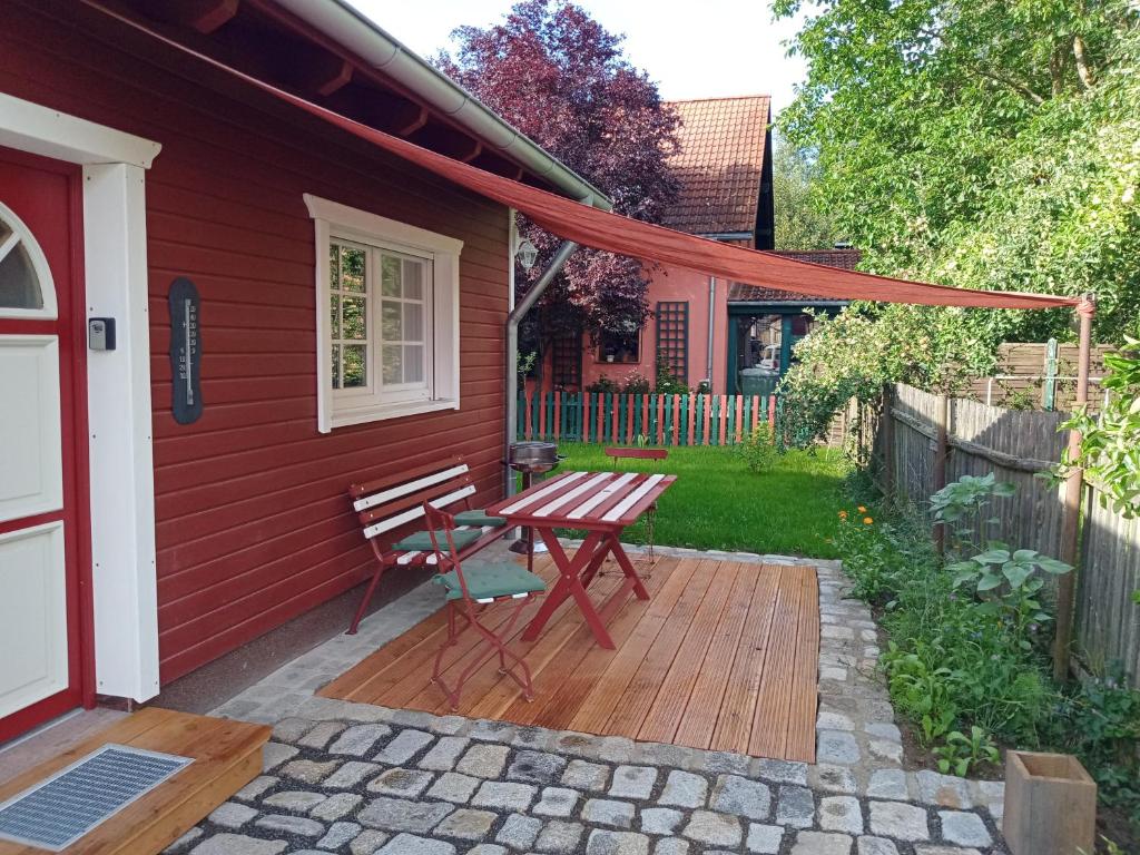 a red house with a wooden table and a bench at Ferienhaus am Wald in Sangerhausen