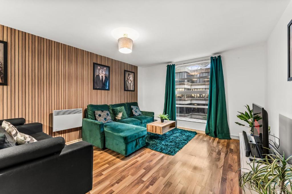 sala de estar con sofá verde y ventana en Spacious Central Manchester Apartment - Sleeps 8, en Mánchester