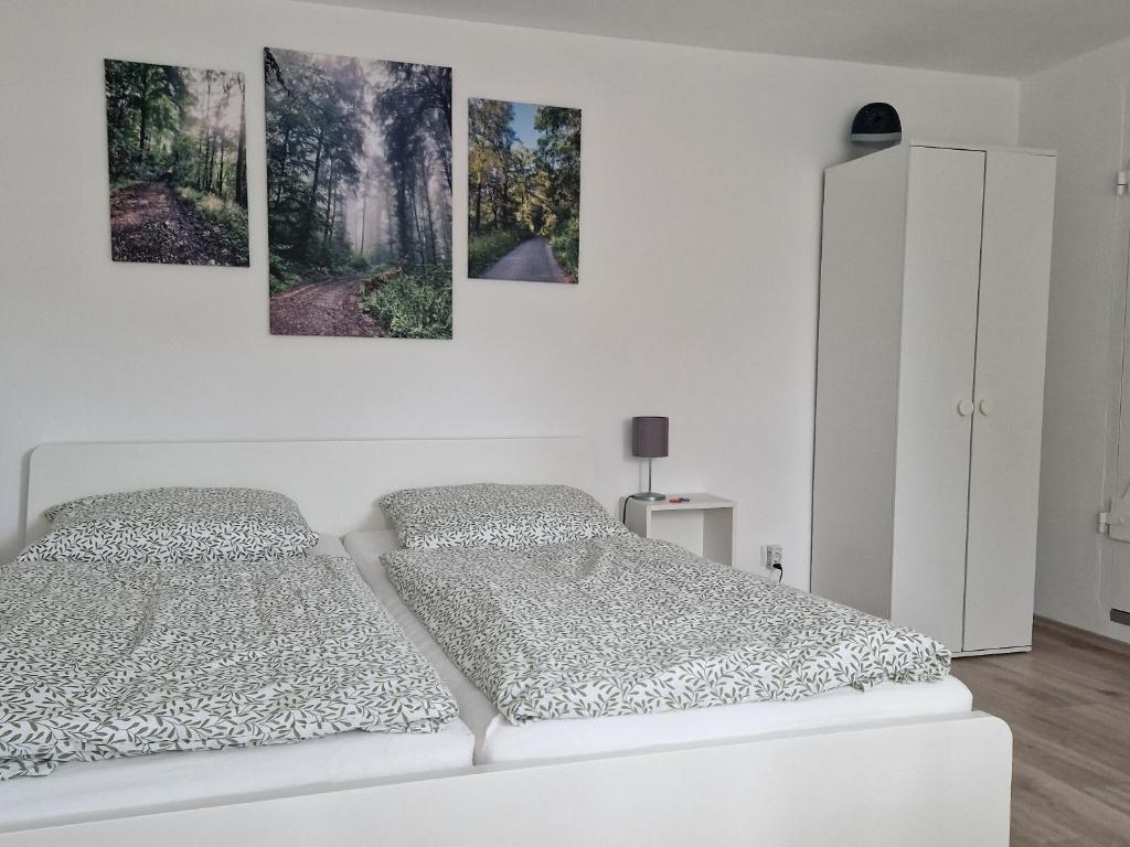 1 Schlafzimmer mit 2 Betten und 3 Gemälden an der Wand in der Unterkunft Waldbergperle Ernsbach in Forchtenberg