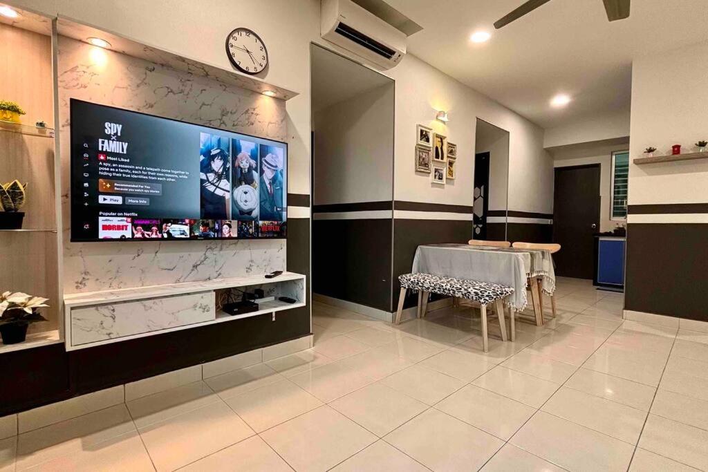 Habitación con TV grande en la pared y mesa. en 'A'ffordable Spacious 6pax S PICE Penang en Bayan Lepas