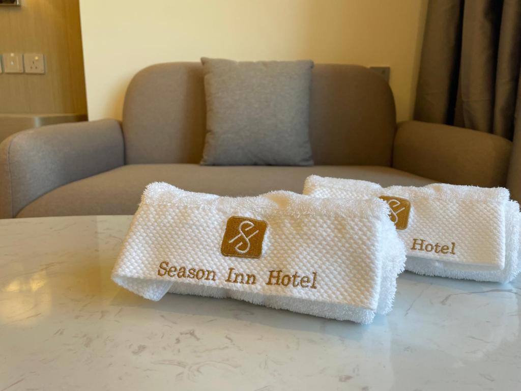 Season Inn Hotel_Bald Sayt في Rustāq: اثنين من الوسائد البيضاء تقف على طاولة أمام أريكة
