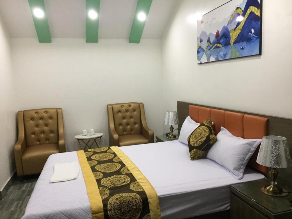 una camera da letto con un letto con due sedie e un quadro di Ánh Sao Hotel - ngõ 42 Liễu Giai - by Bay Luxury a Hanoi