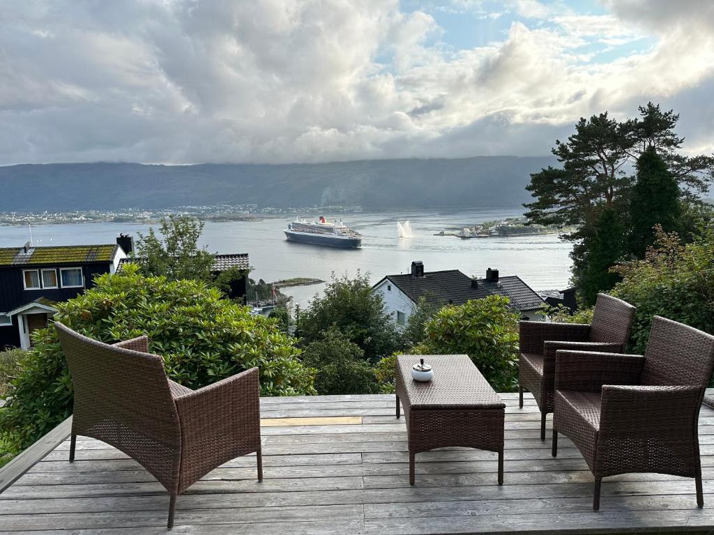 eine Terrasse mit Stühlen und einem Boot im Wasser in der Unterkunft Great place with view to the mountains and fjord in Ålesund
